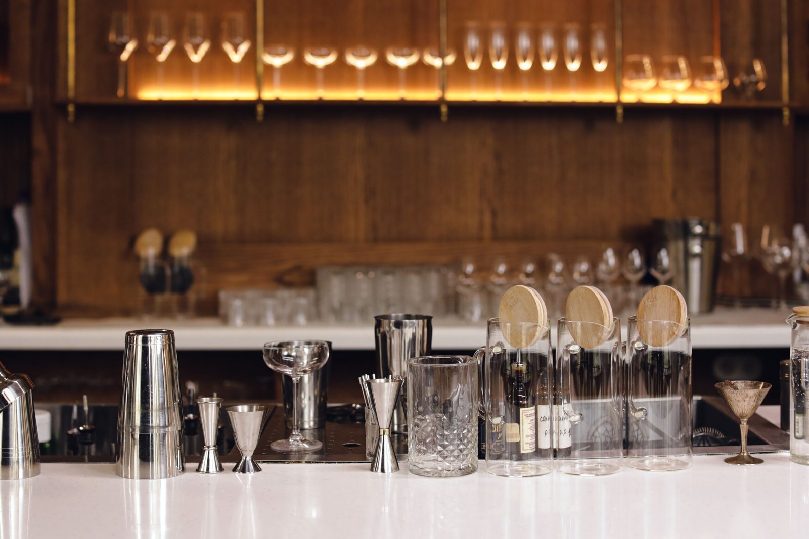 pexels photo 8942209 8942209 A stylish bar counter showcasing various glassware and bar tools in a warm, inviting ambiance.