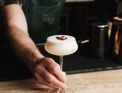 pexels photo 29707878 29707878 A bartender serves an elegant cocktail topped with a garnish at a trendy bar setting.