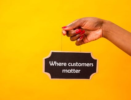 pexels photo 7563603 7563603 A close-up of a hand holding a sign stating Where customers matter against a bright yellow background.